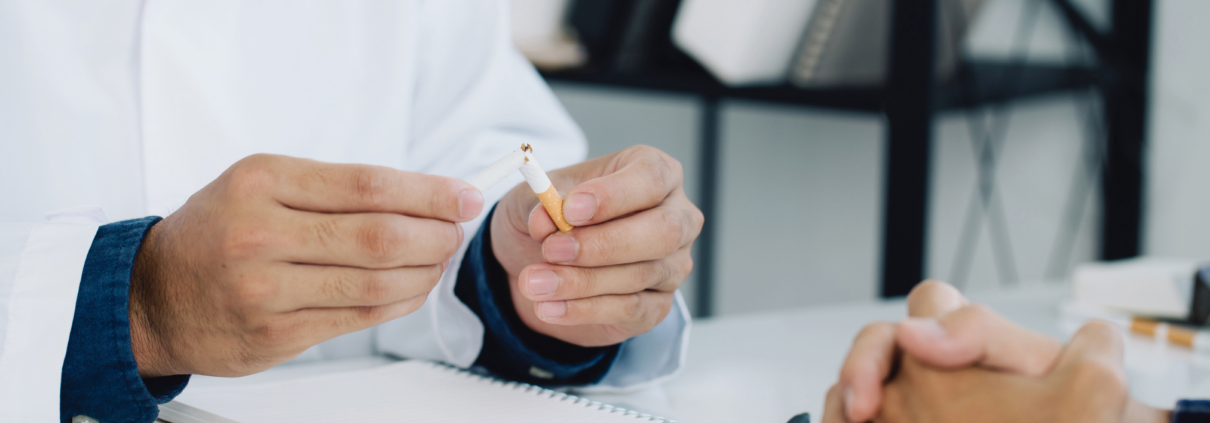 Ein Arzt zeigt einem Patienten, wie eine Zigarette zerbrochen wird, um auf die Gefahren des Rauchens hinzuweisen.